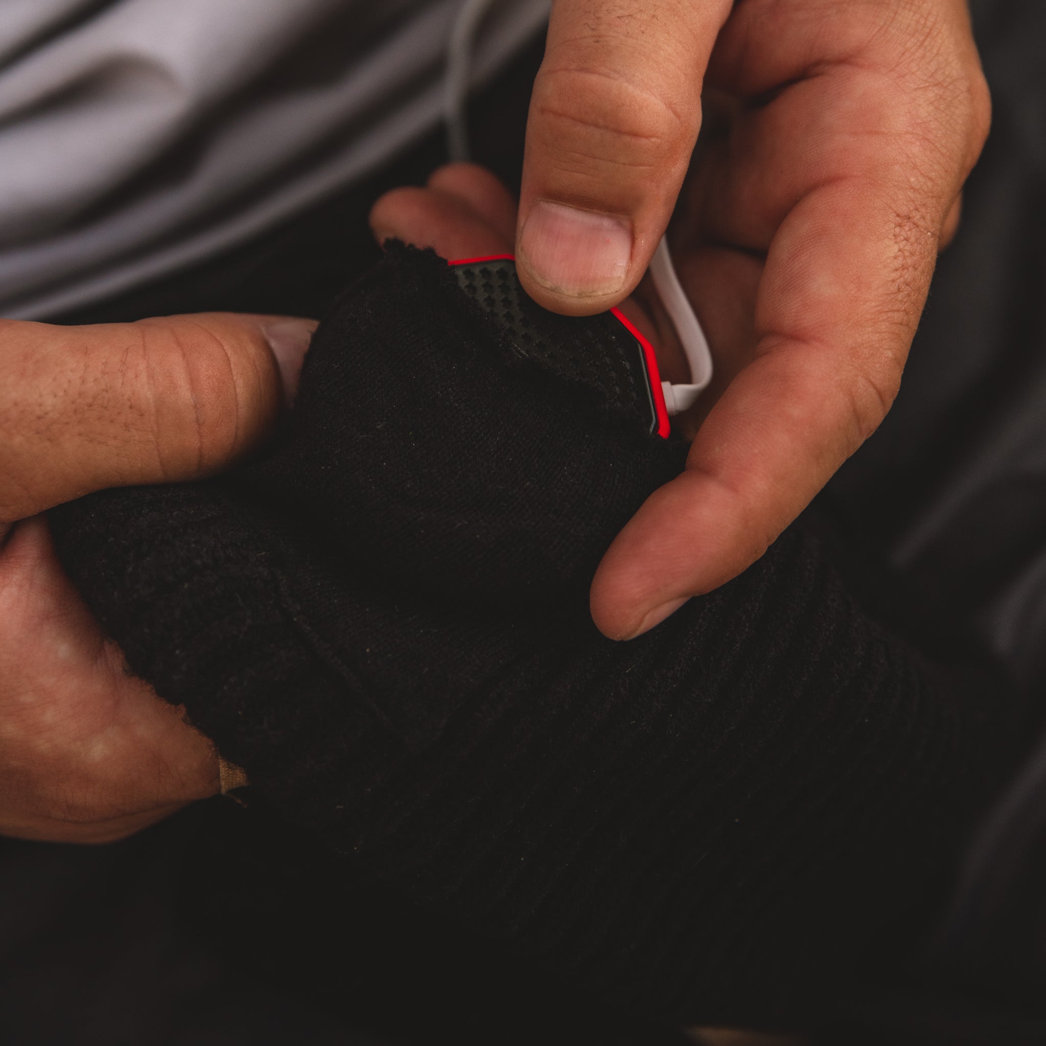 Image of a man's hands putting the CHIPS into pockets of the Shred Beanie.